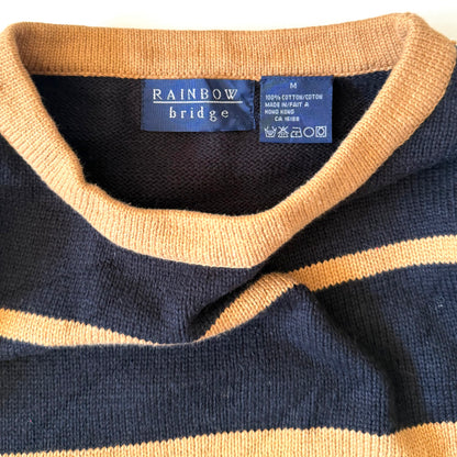 Close-up of a navy and beige striped sweater with a brand label on a white background