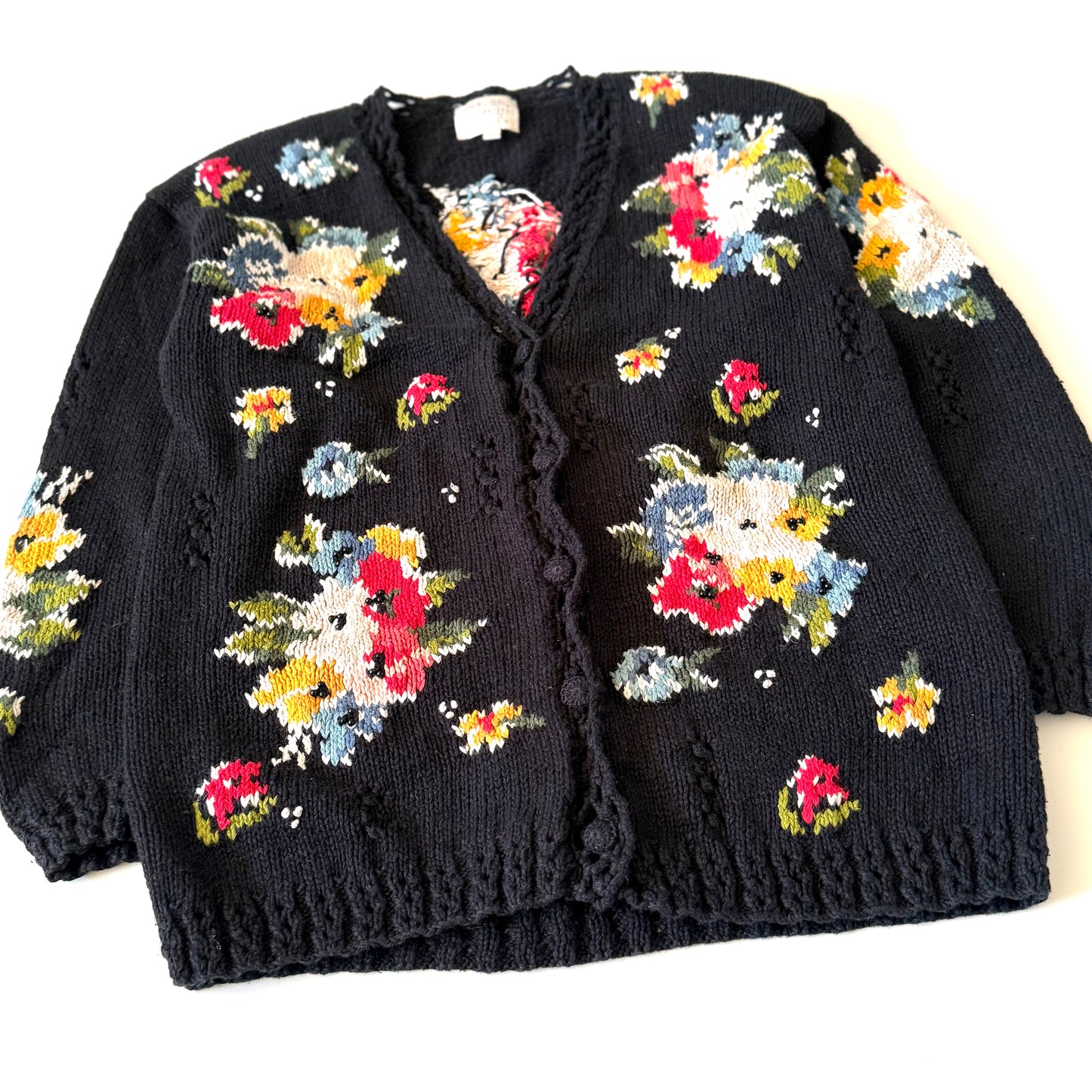 Black cardigan with colorful floral patterns on a white background