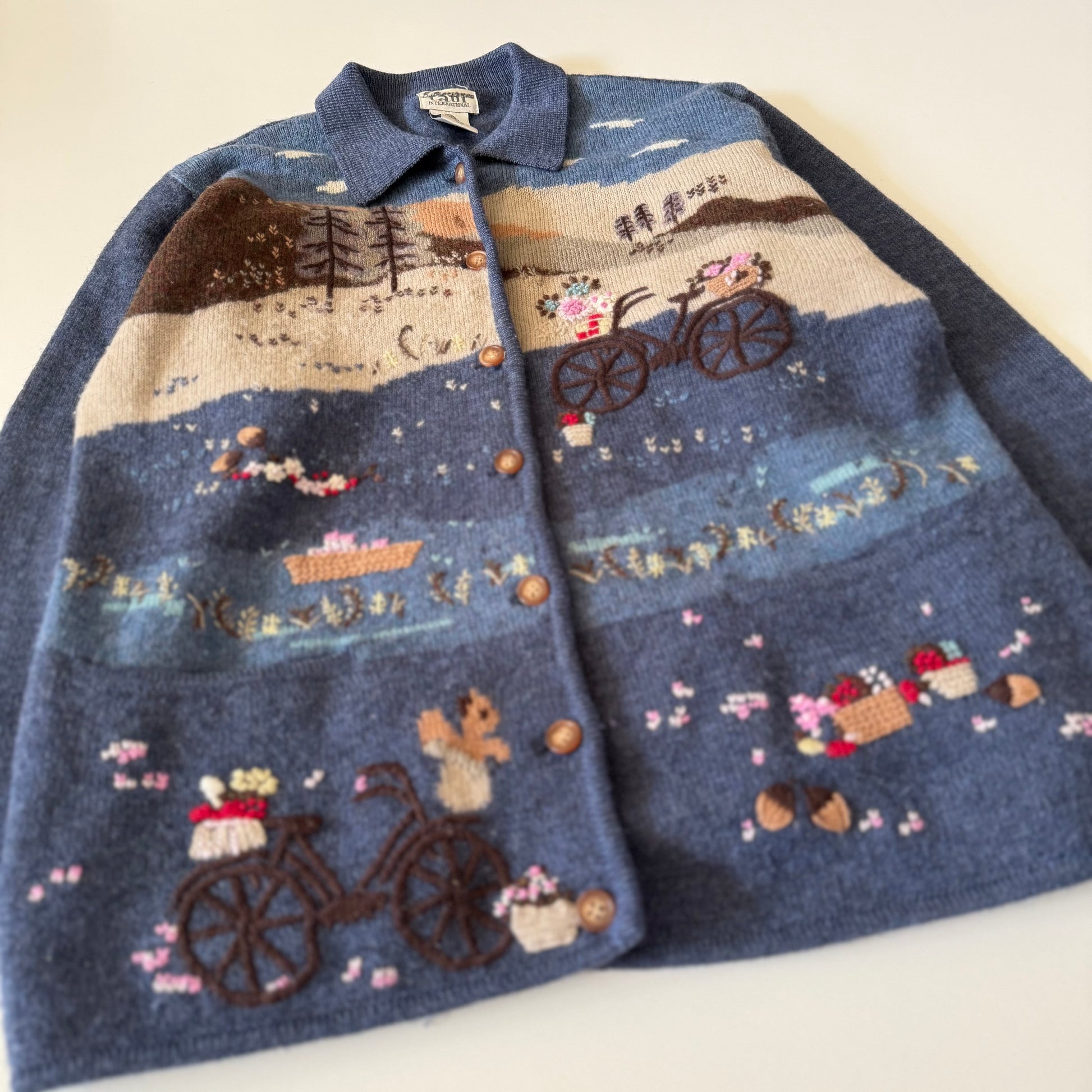 Blue embroidered jacket with scenic design on a white background