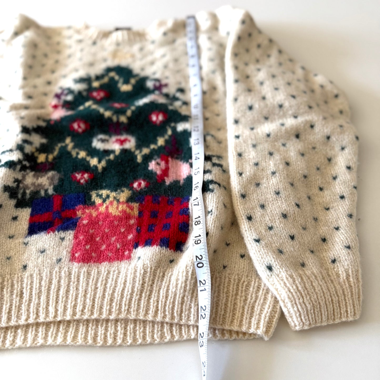 Knitted sweater with festive design and polka dot pattern, with a measuring tape draped over it.