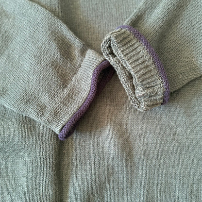 Close-up of a gray garment with purple trim on a matching fabric background
