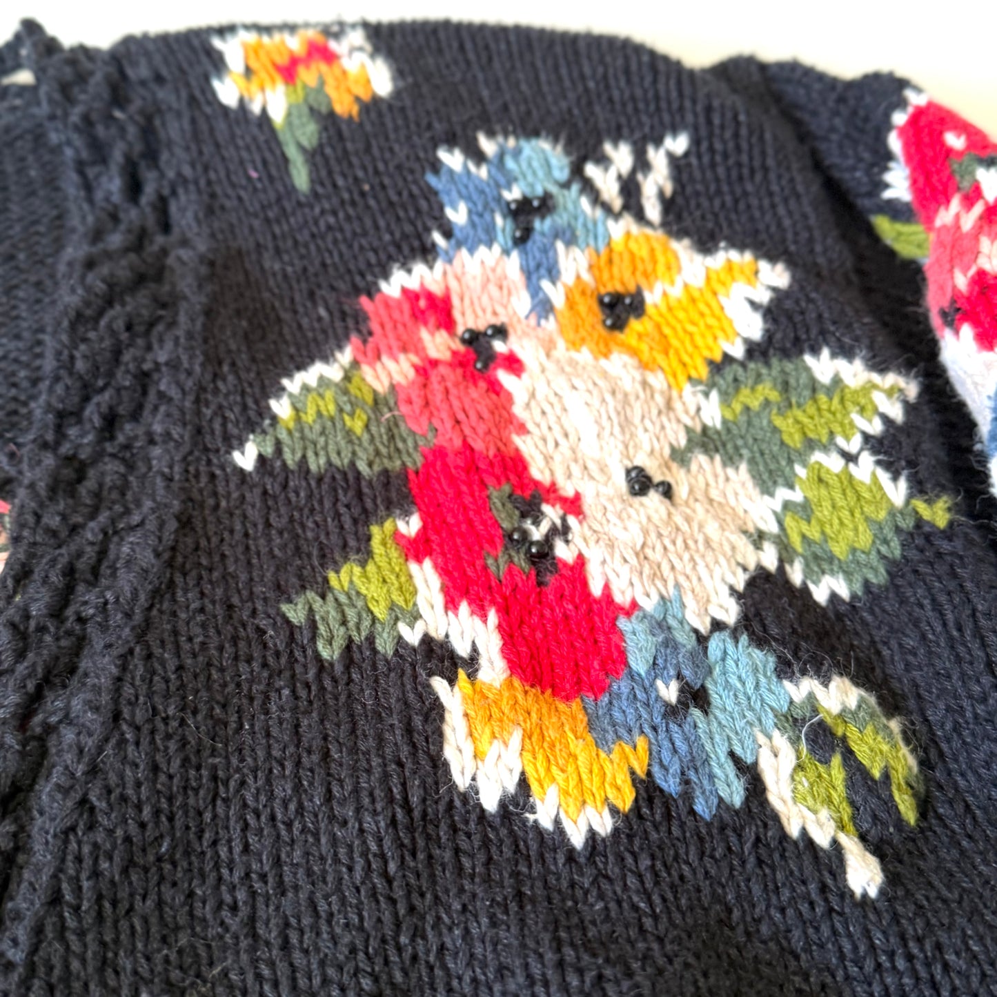 Close-up of a knitted item with colorful floral pattern on a dark background