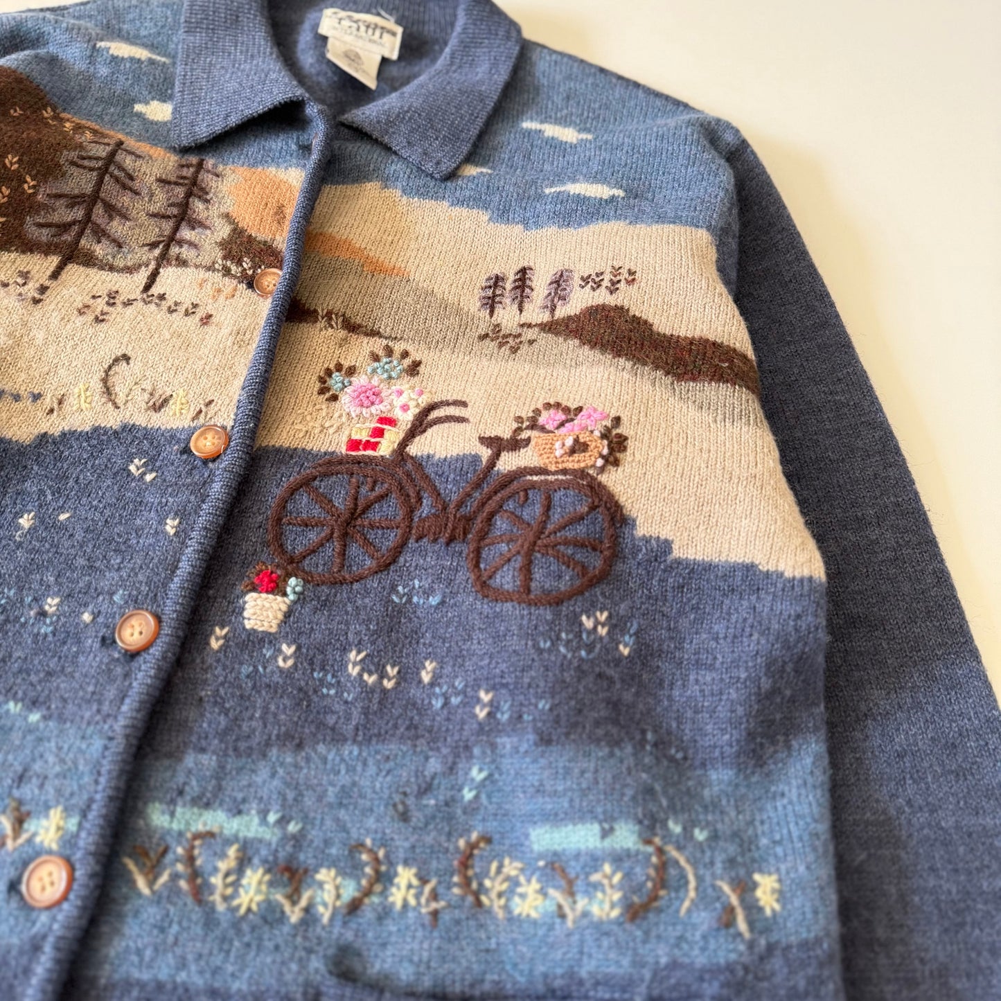 Textured fabric with embroidered bicycle and floral design on a blue background