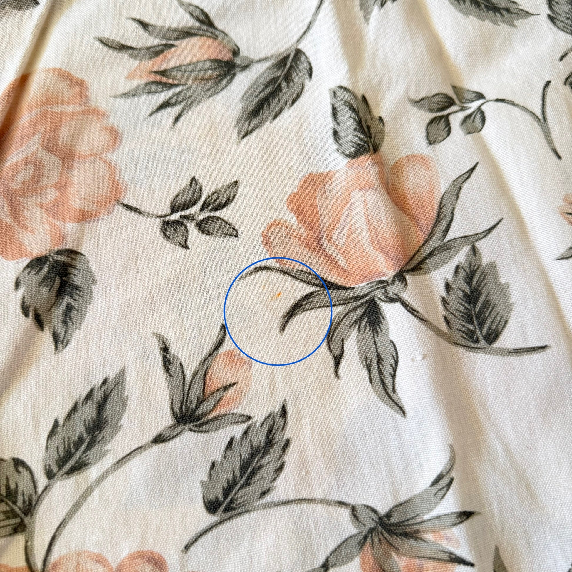 Floral patterned fabric with a blue circle highlighting an imperfection.
