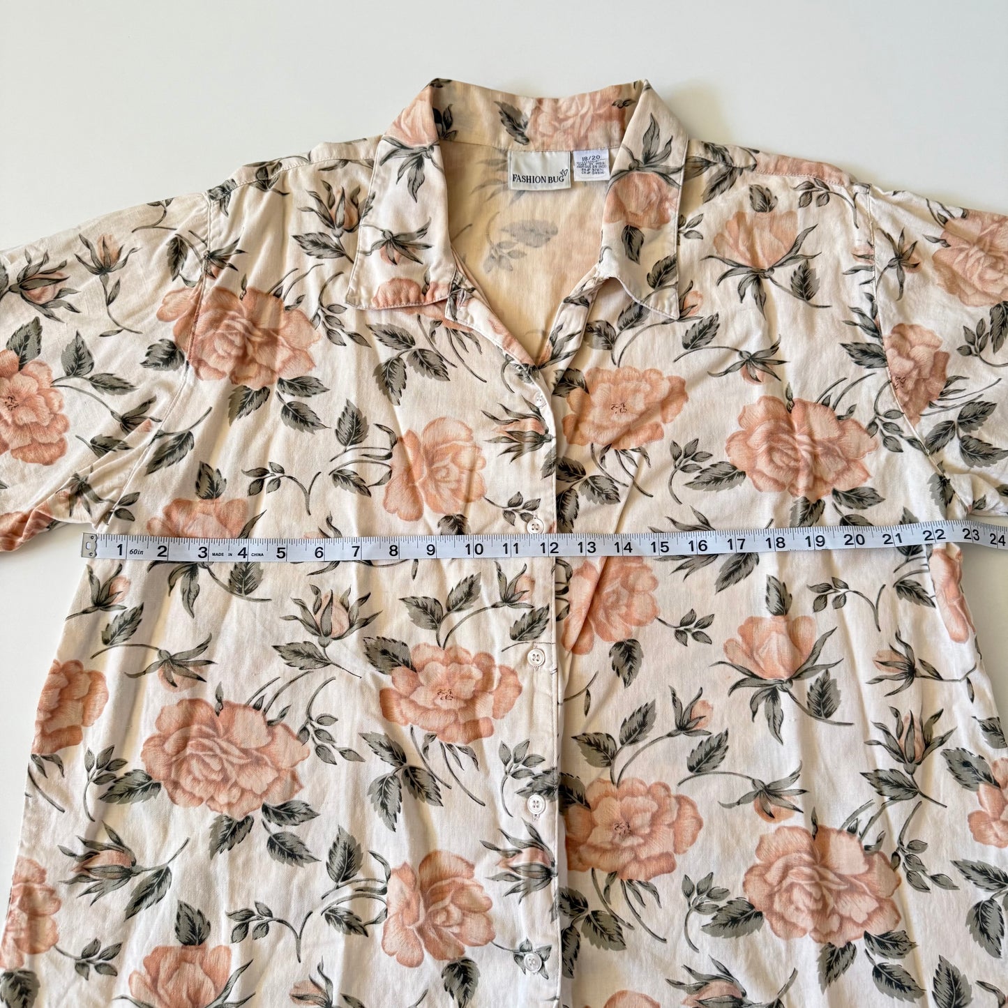 Floral patterned shirt with a measuring tape laid across it on a white background