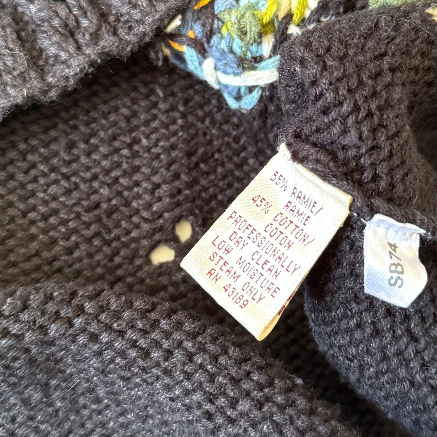 Close-up of a knitted garment with care label and brand tag.