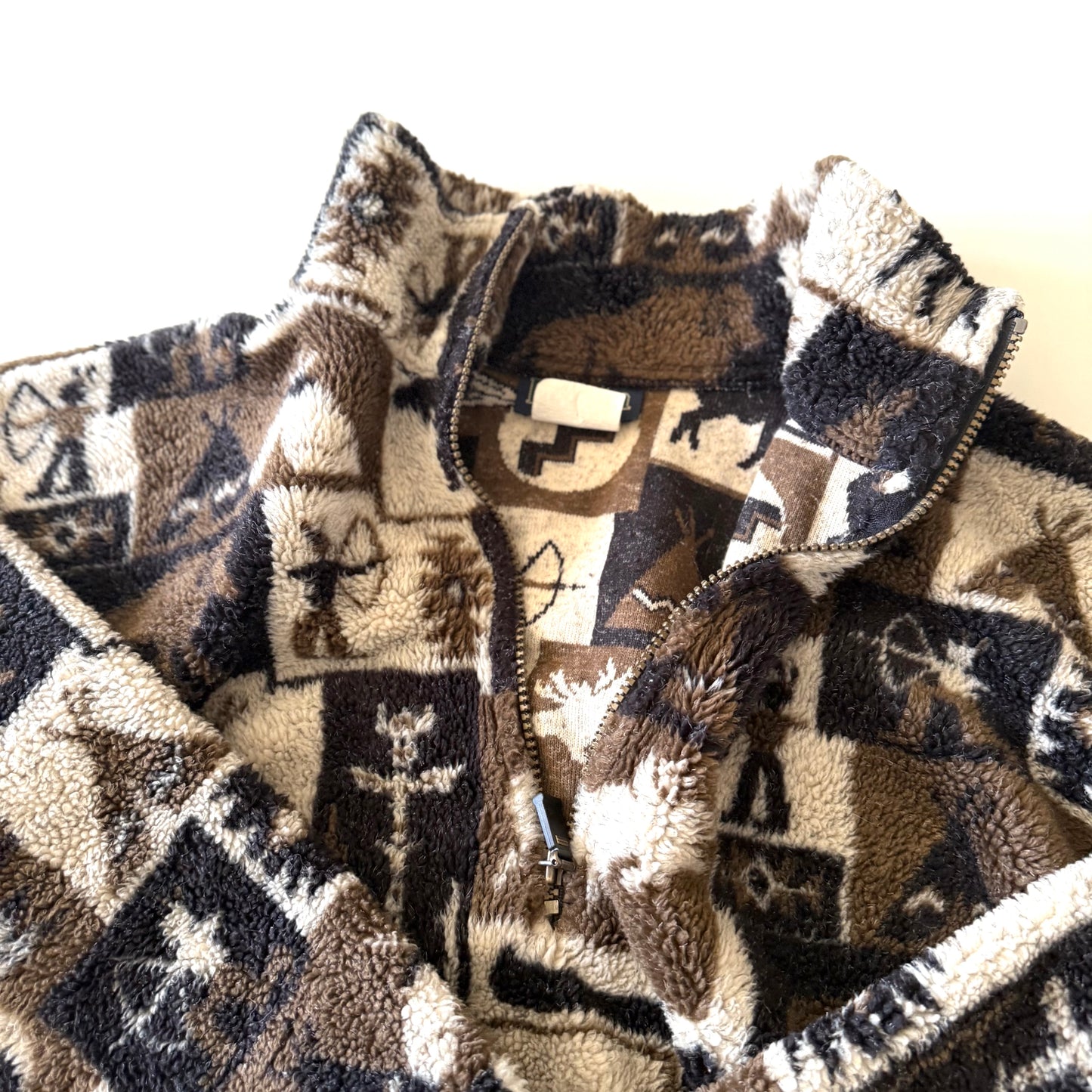 Moose and other camping motif quarter zip fleece on a white background. This photo is a close up of the zipper open. 