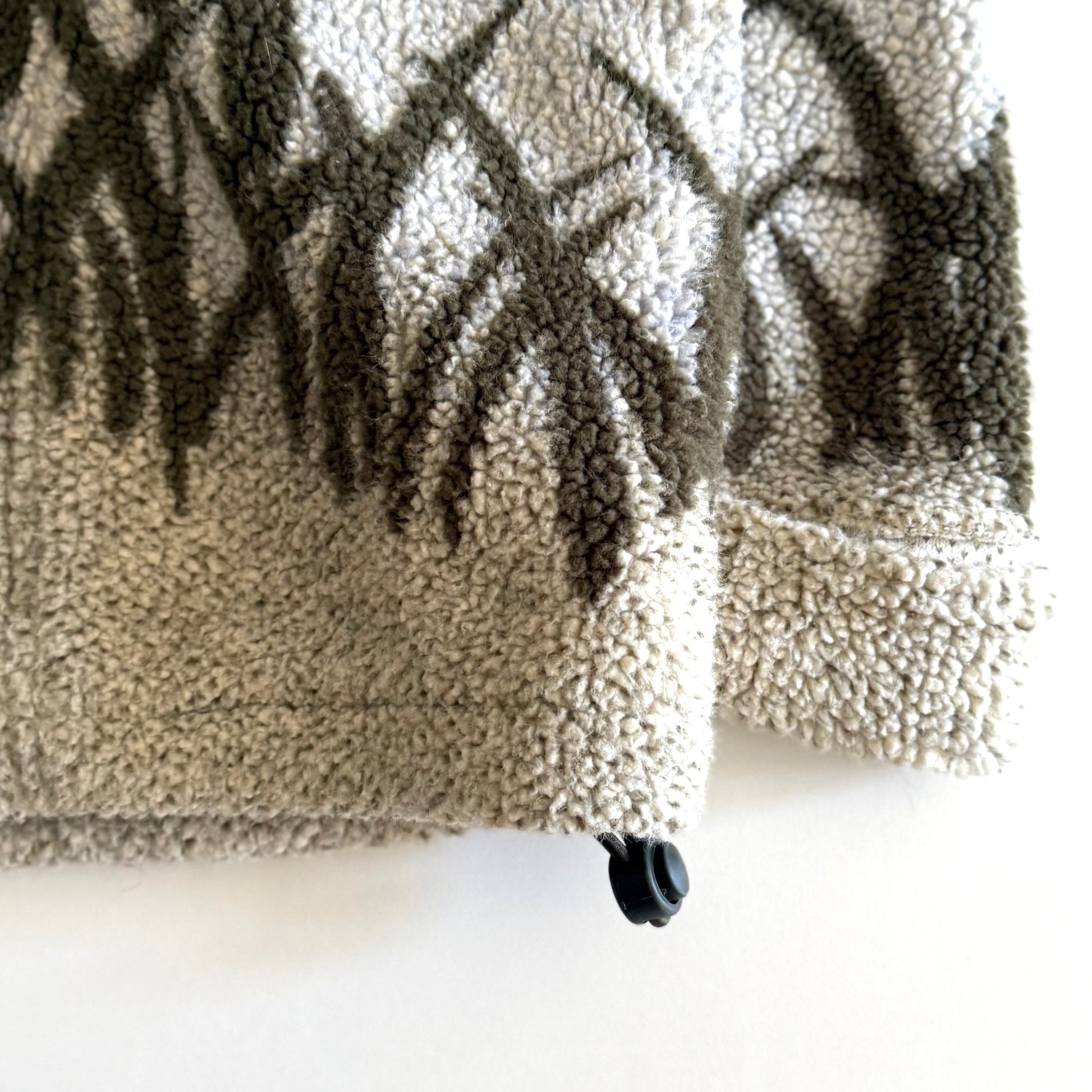 Fleece textured sweater with a mountain marsh forest scene on it, and a zippered close - on a white backdrop. 