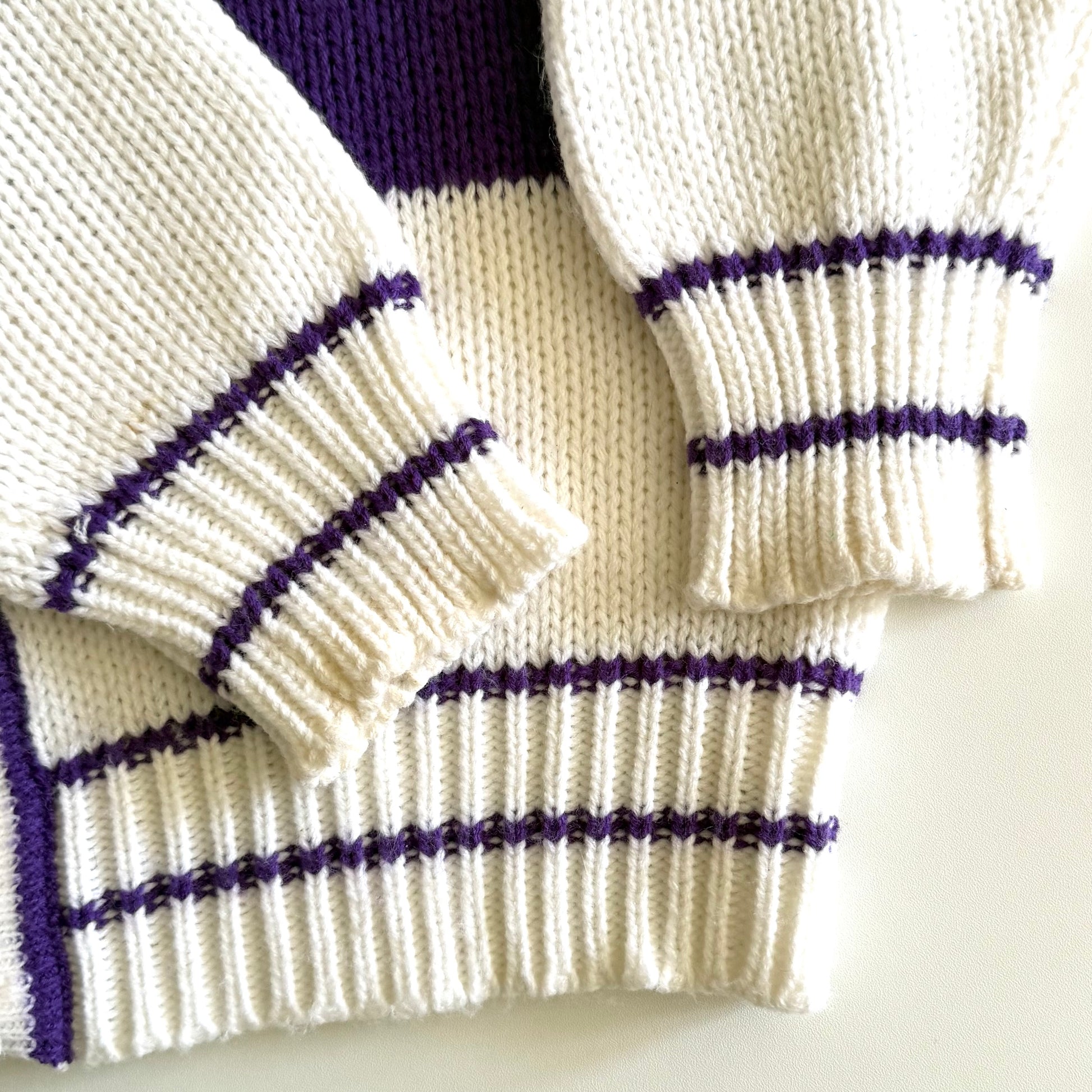 Close up the sleeve of... 1990's preppy style - purple and white striped cardigan on a white backdrop. 