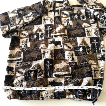 Moose and other camping motif quarter zip fleece on a white background with a measuring tape on it. 