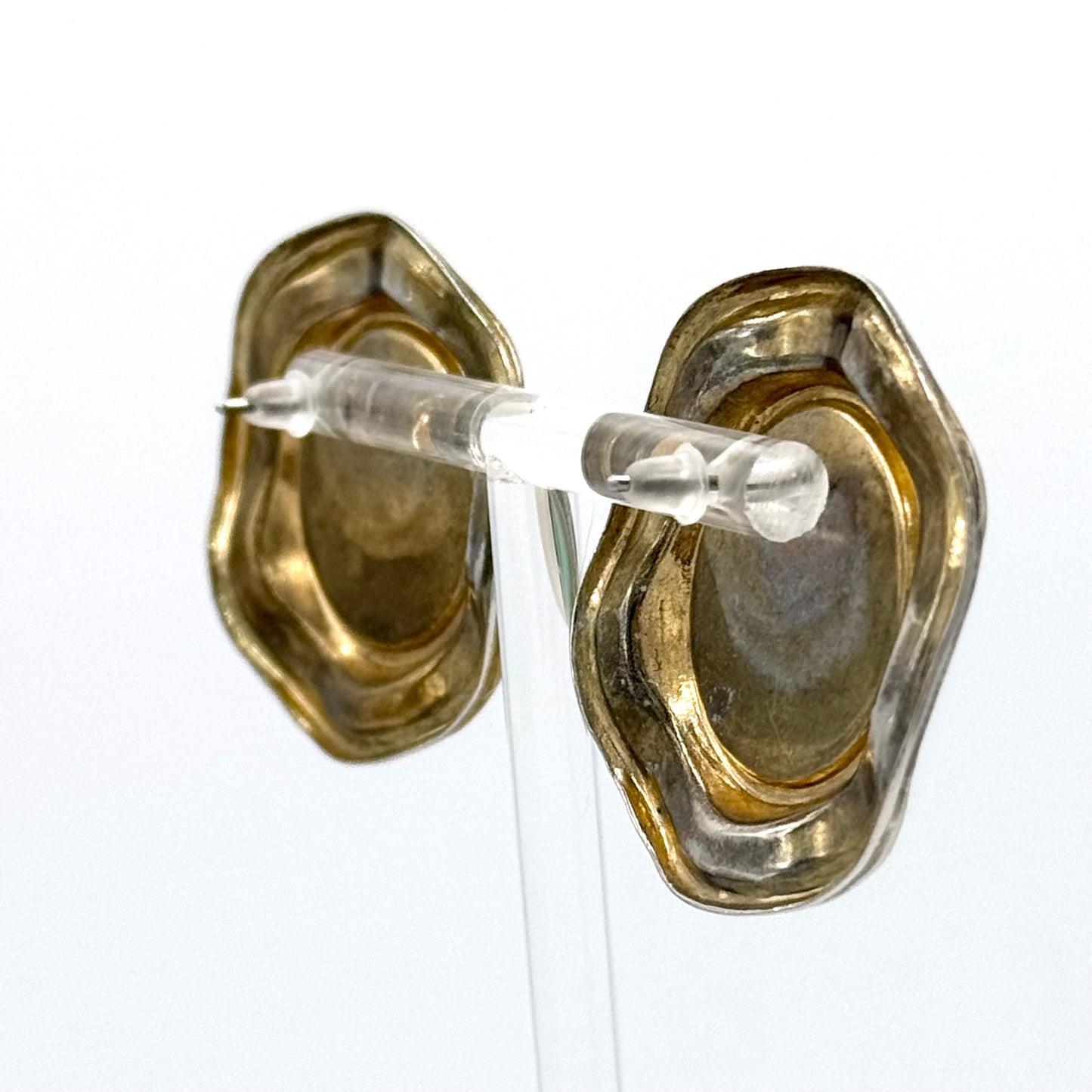 Gold earring with clear silicone stoppers on a white background