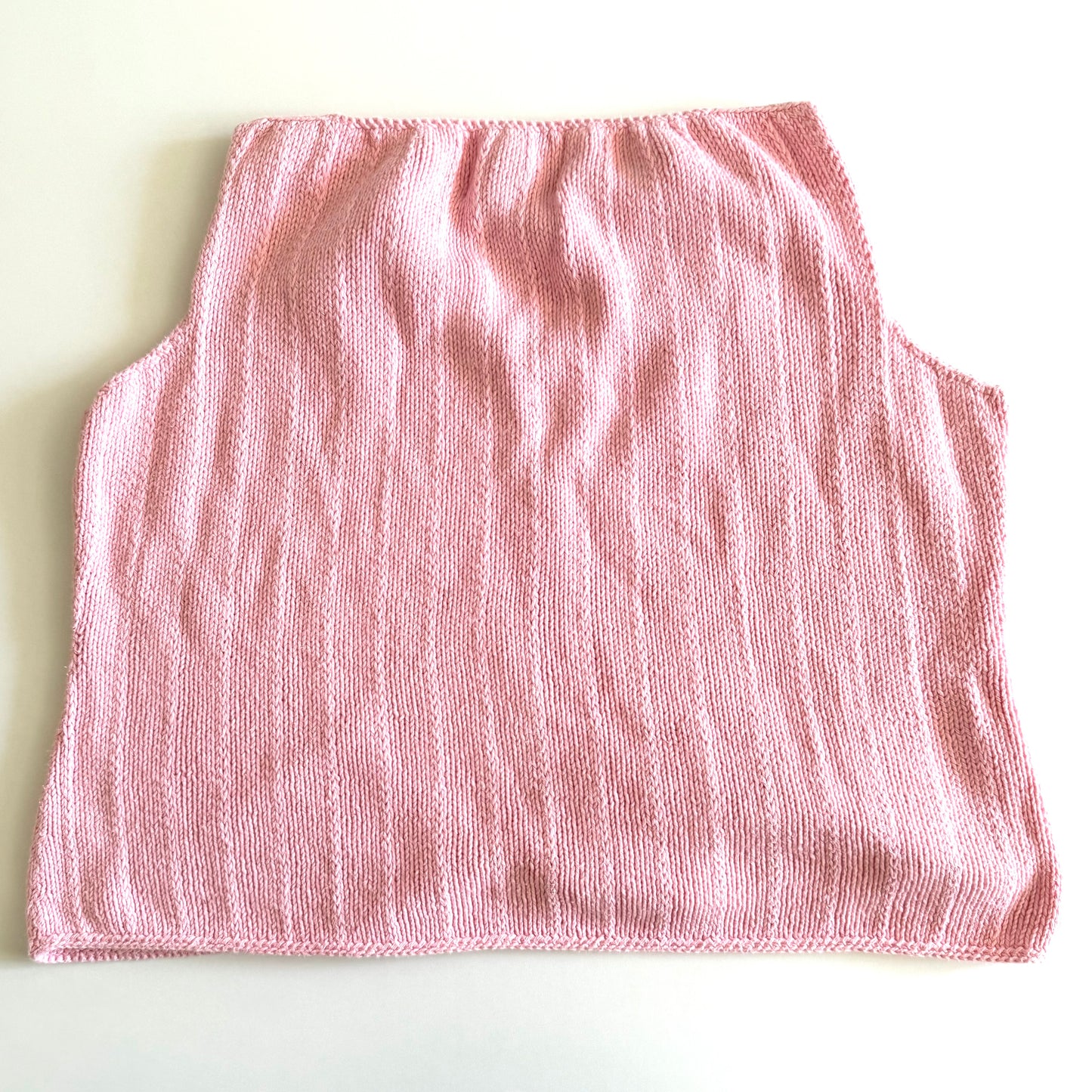 Back side of Light pink knit style tank top, with folded out collar opening on a white backdrop. 