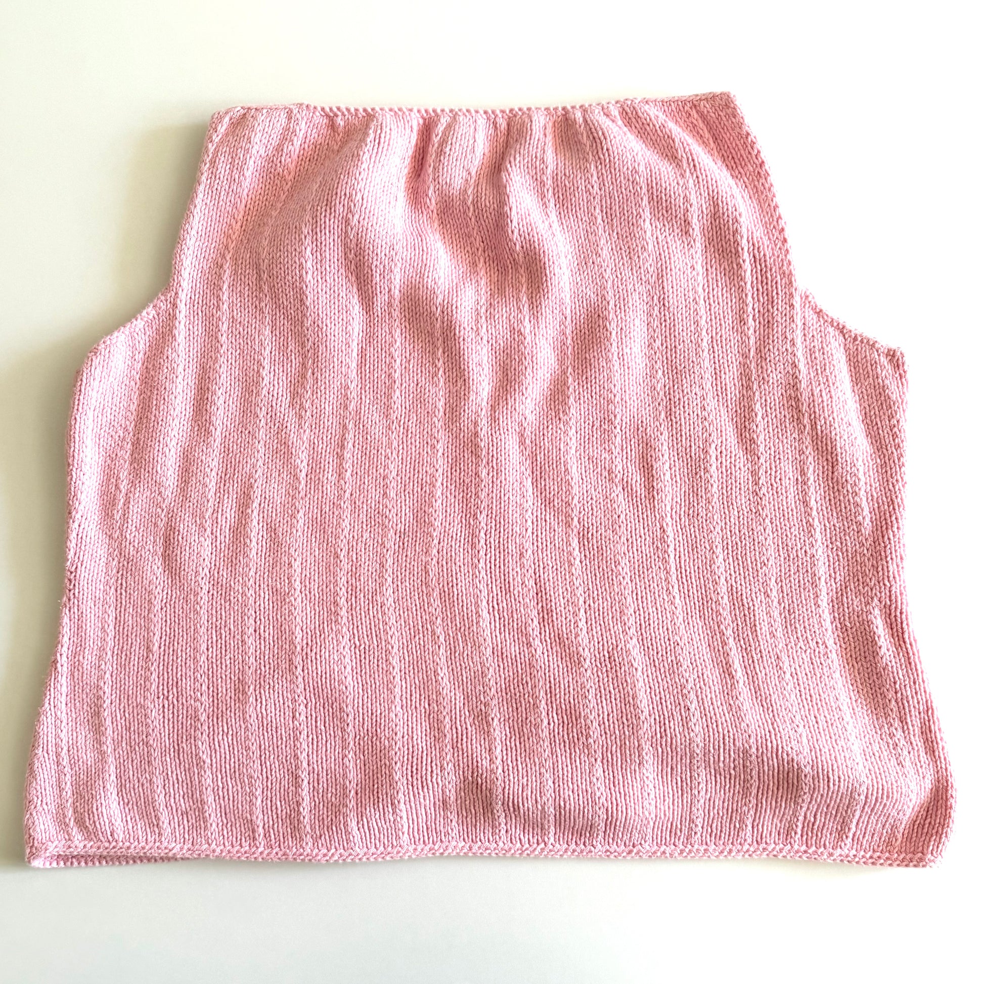 Back side of Light pink knit style tank top, with folded out collar opening on a white backdrop. 