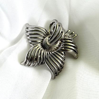 Silver brooch on a white fabric background