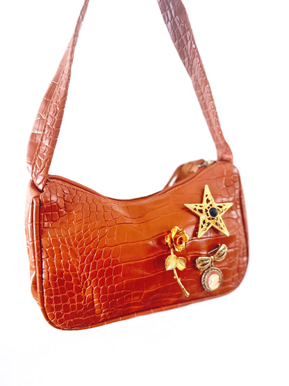 Brown handbag with decorative elements on a white background